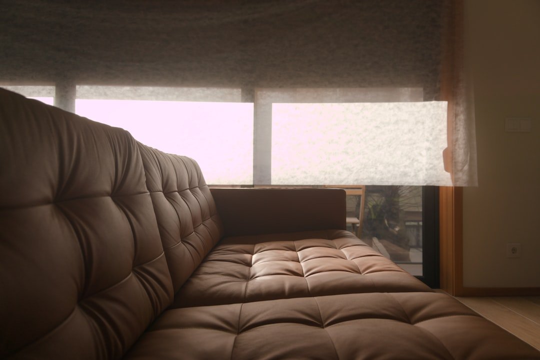 a brown leather couch sitting in front of a window