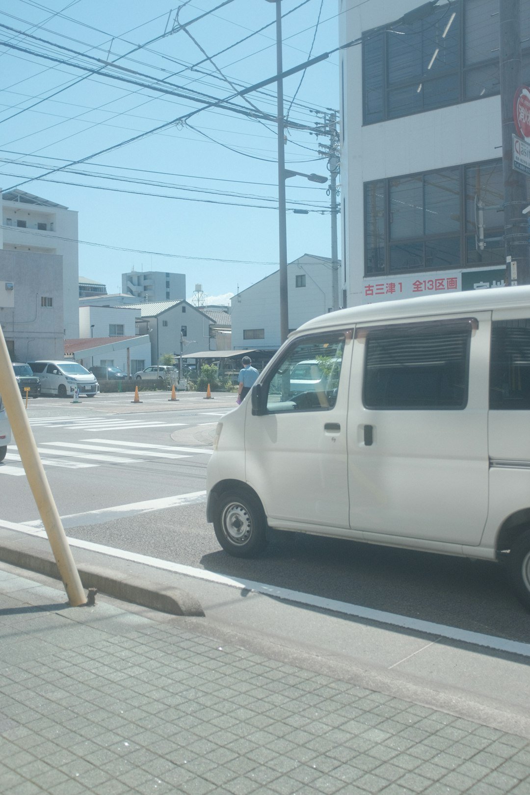 a white van driving down a street next to a tall building