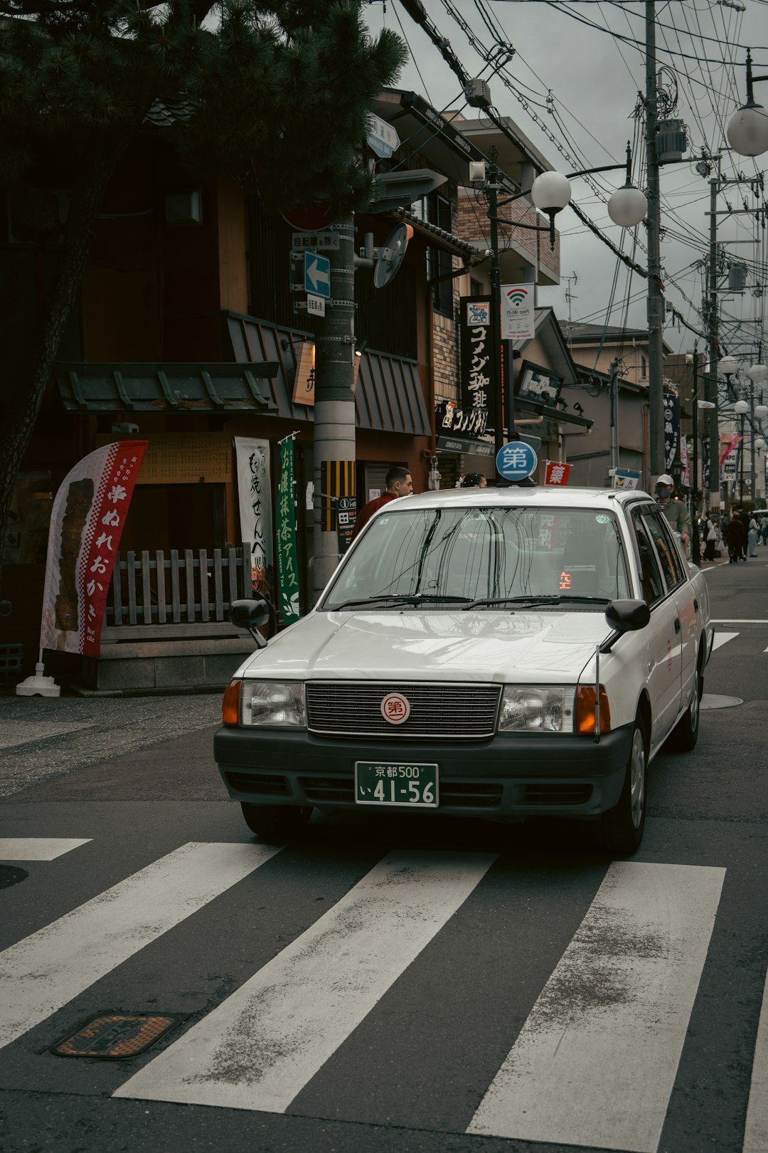 A japanese taxi crosses a crosswalk in the street.
