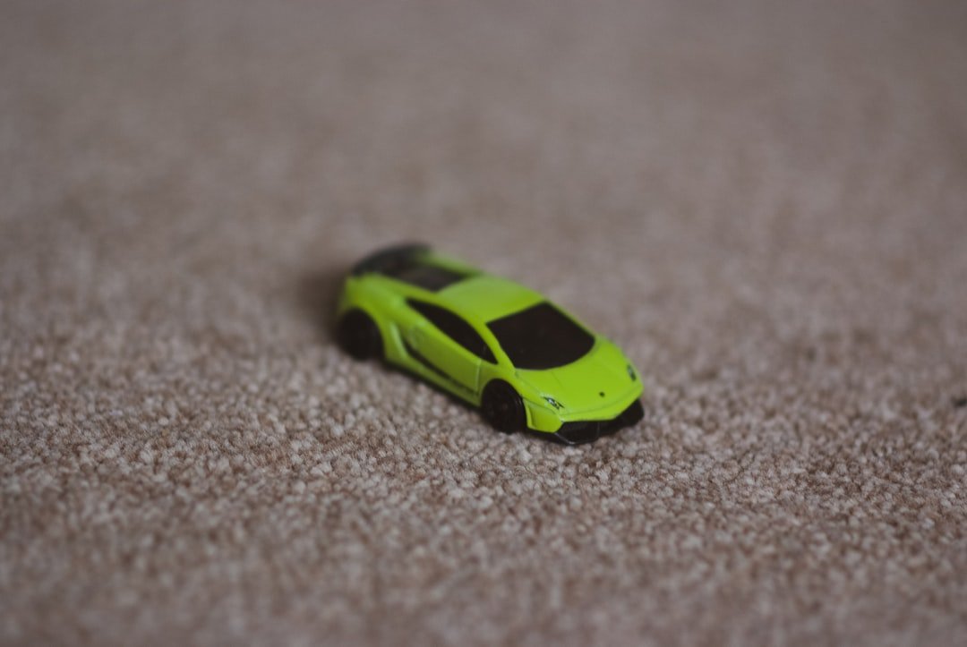 a green toy car sitting on top of a carpet
