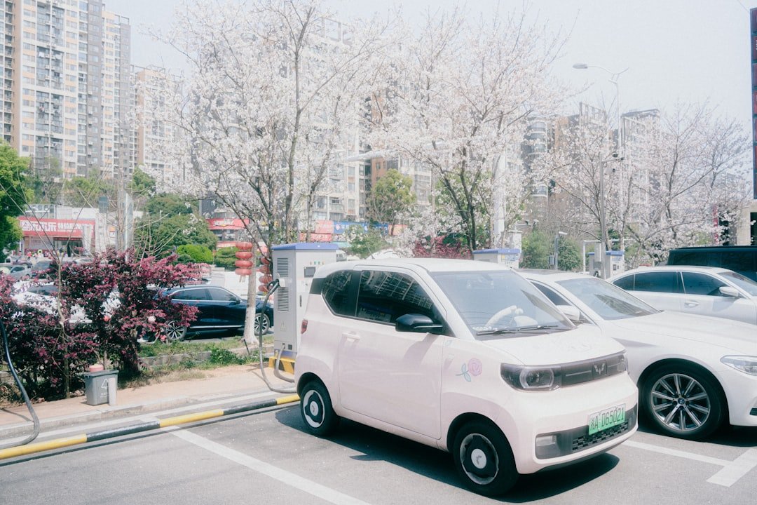 A pink ev is charging in a city parking lot.