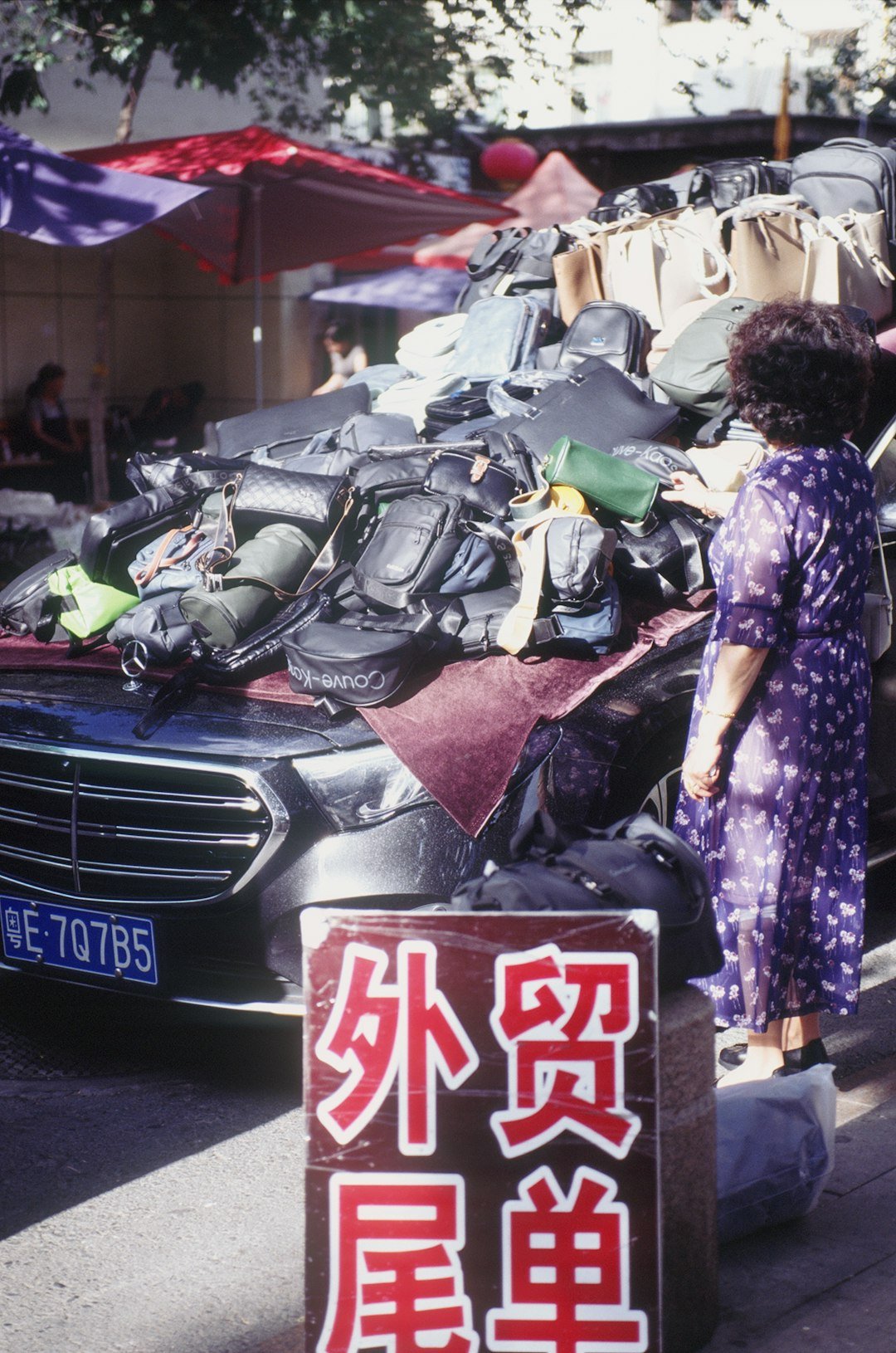 Woman looking at pile of bags on car hood