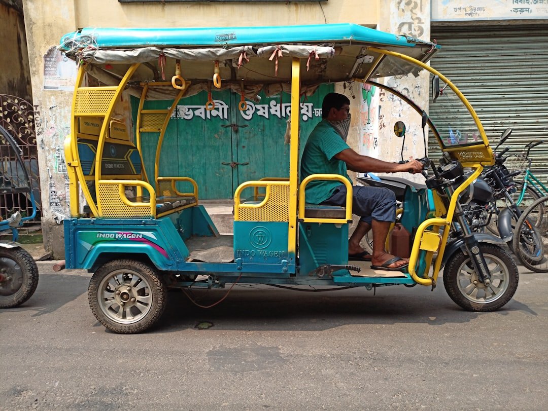 man in blue shirt riding blue and yellow auto rickshaw
