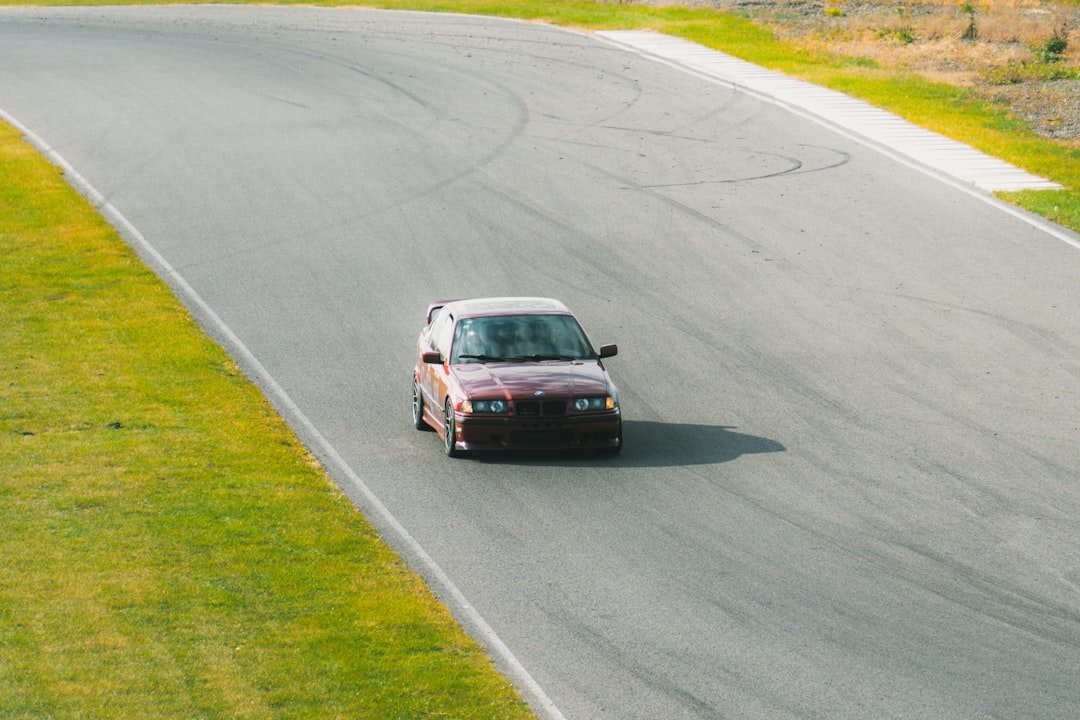 A car driving down a road next to a lush green field