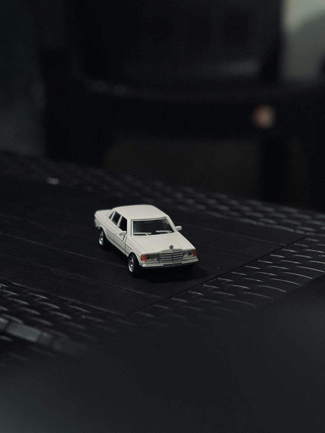 A white toy car sits on a black surface.