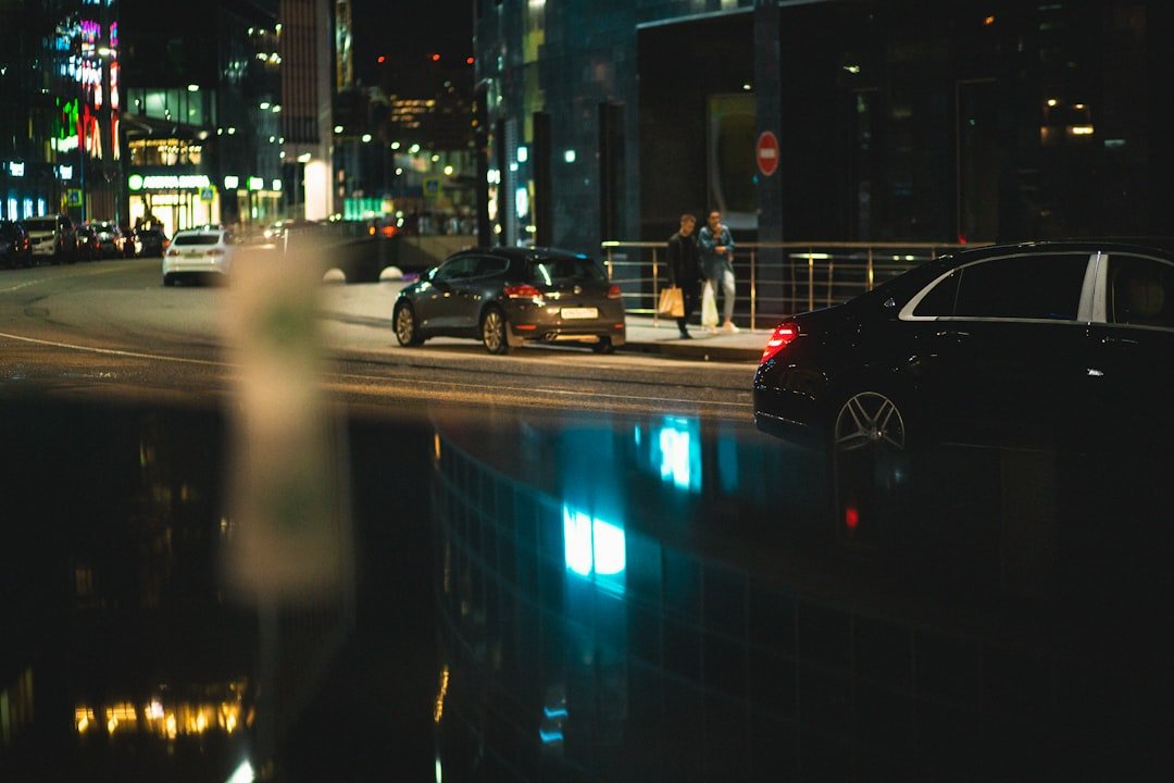 a city street at night with cars parked on the side of the road