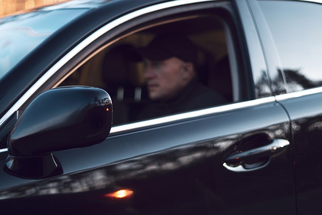 Man wearing a black cap driving a black car