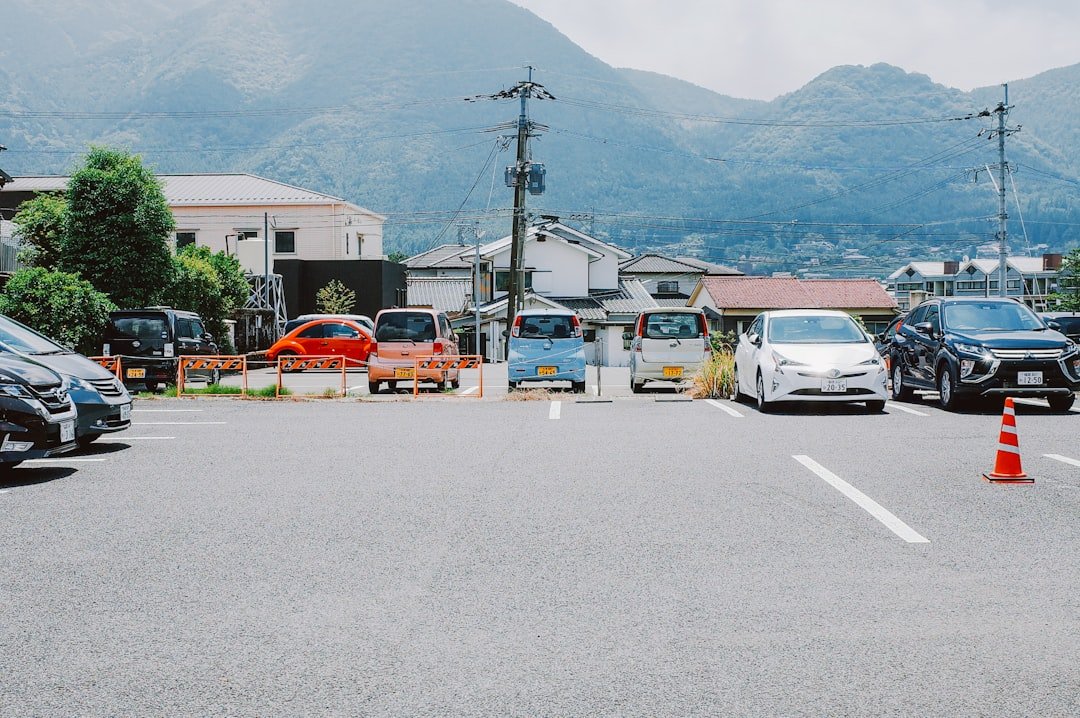 Cars parked in a lot with mountains in background.