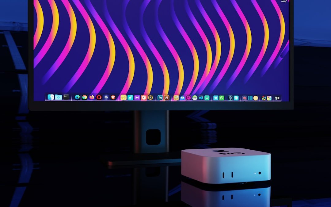 Computer monitor displaying abstract colorful waves and small desktop computer.