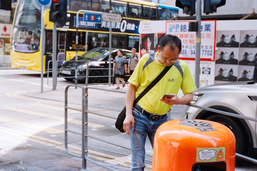 Man looking at his phone on a busy street.