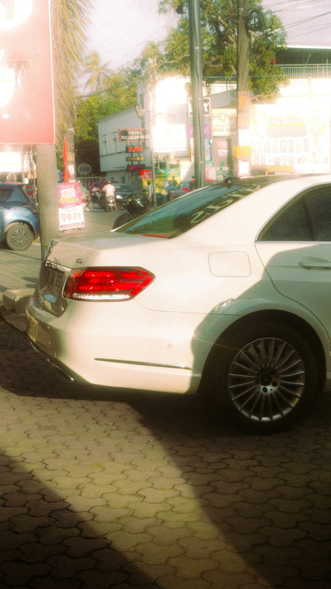 White sedan parked on a cobblestone street.