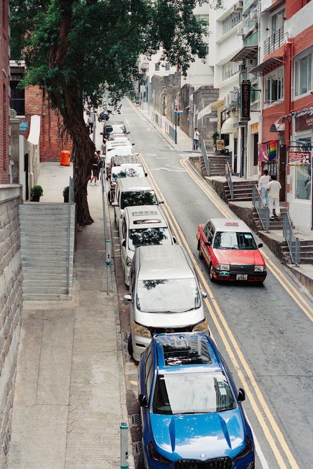 Cars parked on a steep, narrow city street.