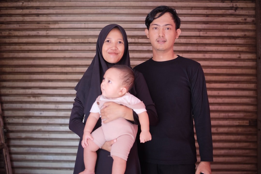 a man and a woman standing next to each other holding a baby