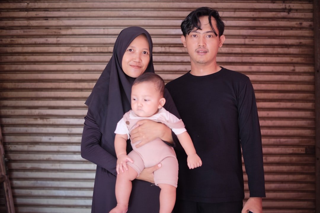 a man and a woman standing next to each other holding a baby