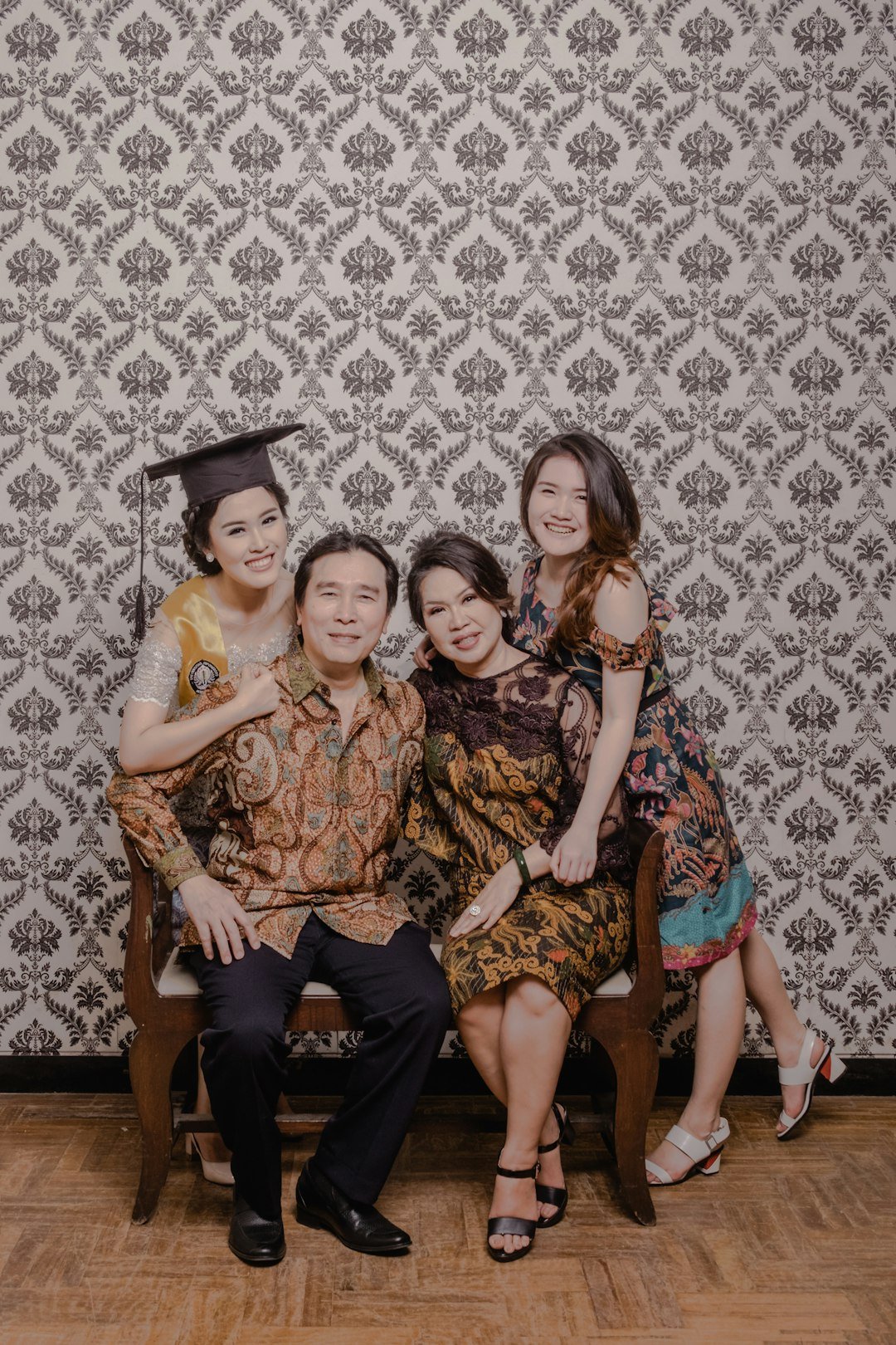 man in black academic dress sitting beside woman in blue and brown floral dress