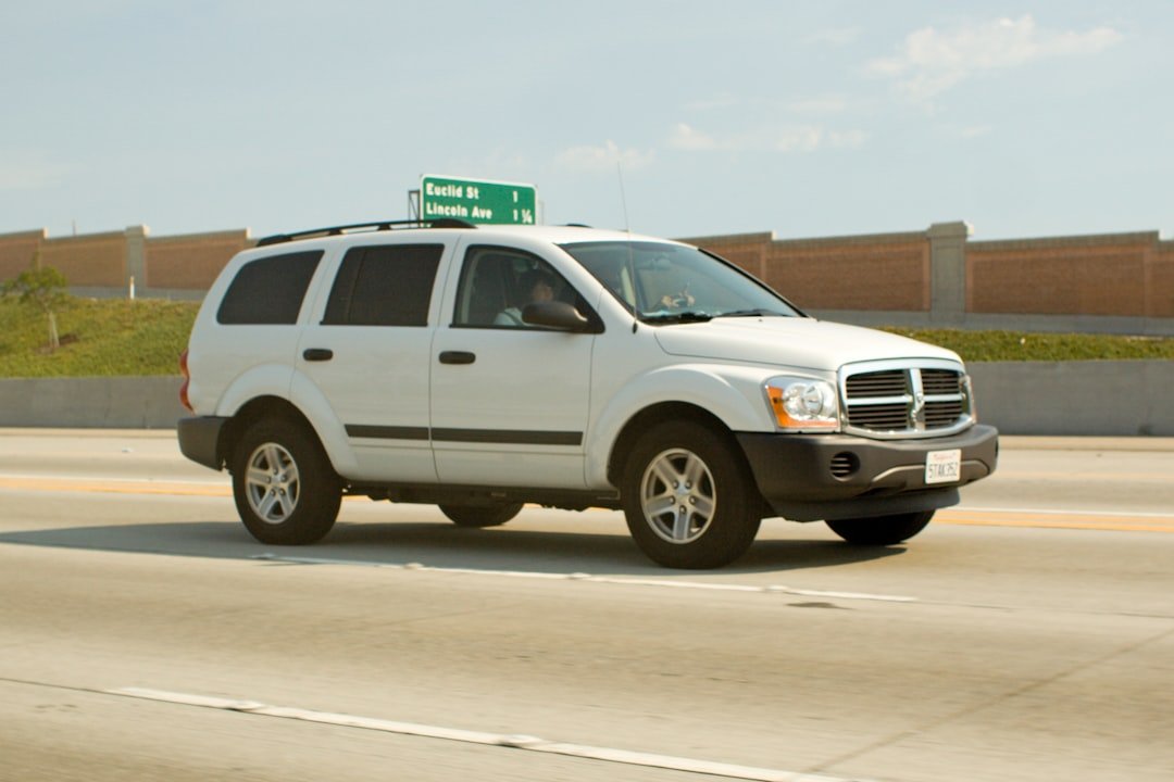White suv driving on a highway under a clear sky.
