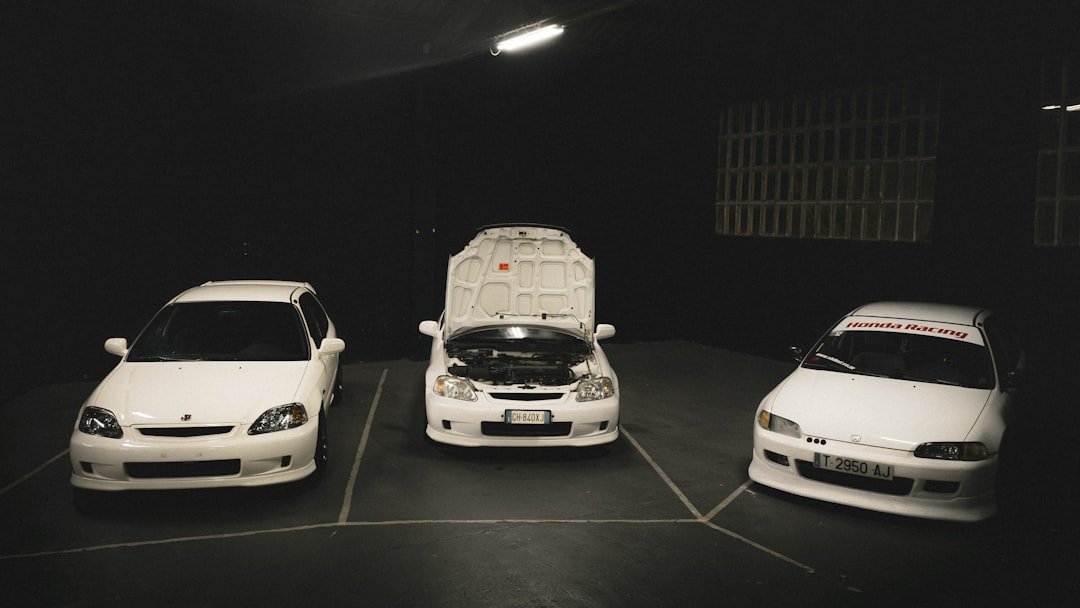 Three white cars parked in a dark garage