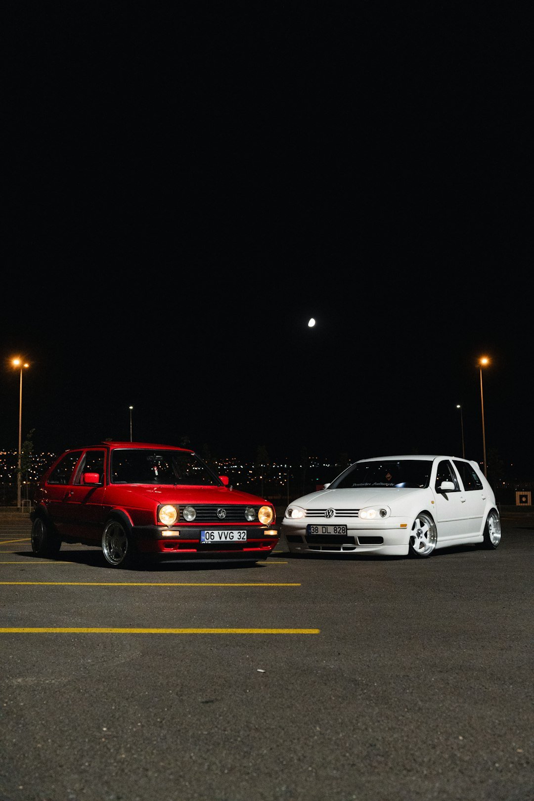 Two cars parked in a parking lot at night