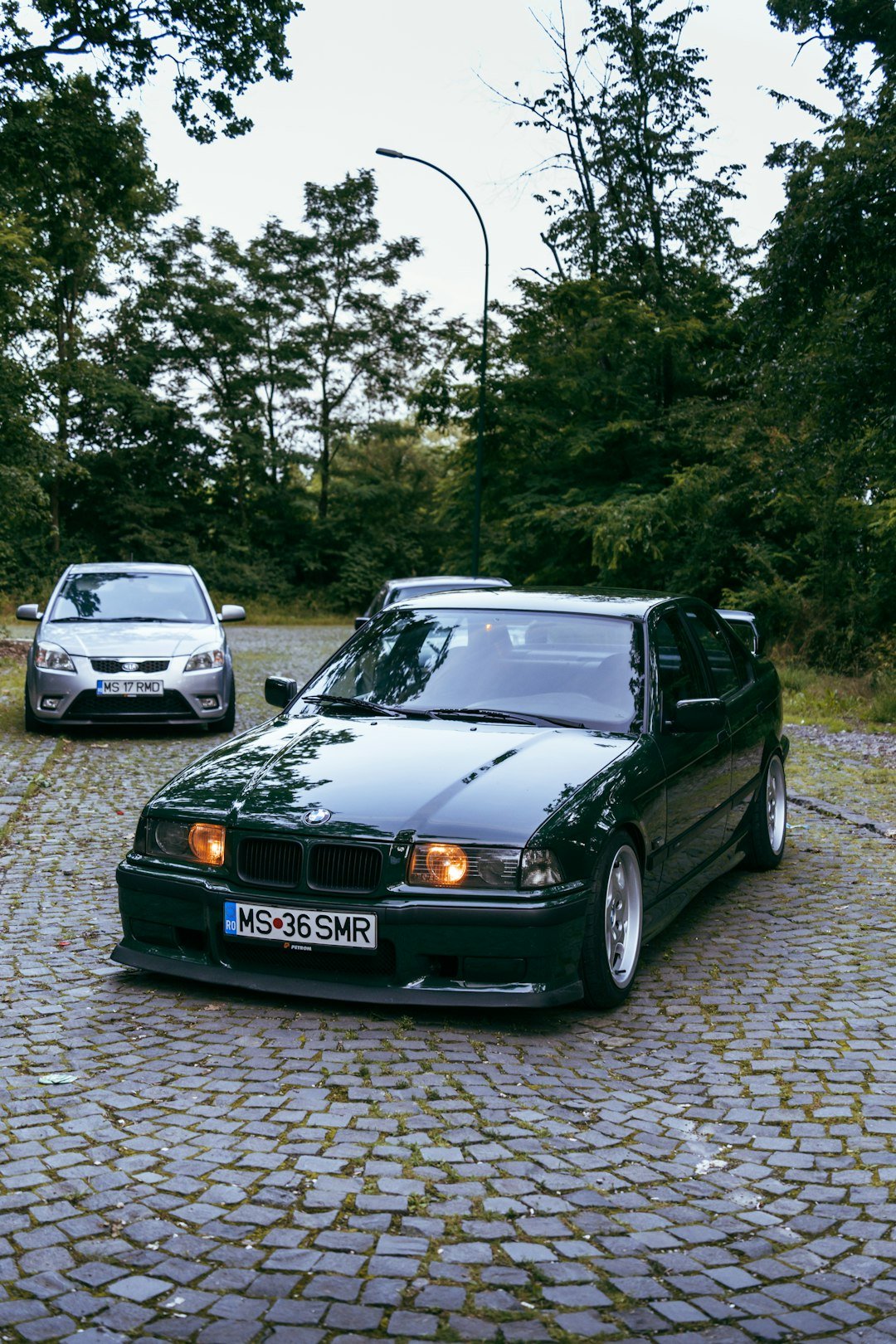 a couple of cars parked on a cobblestone road