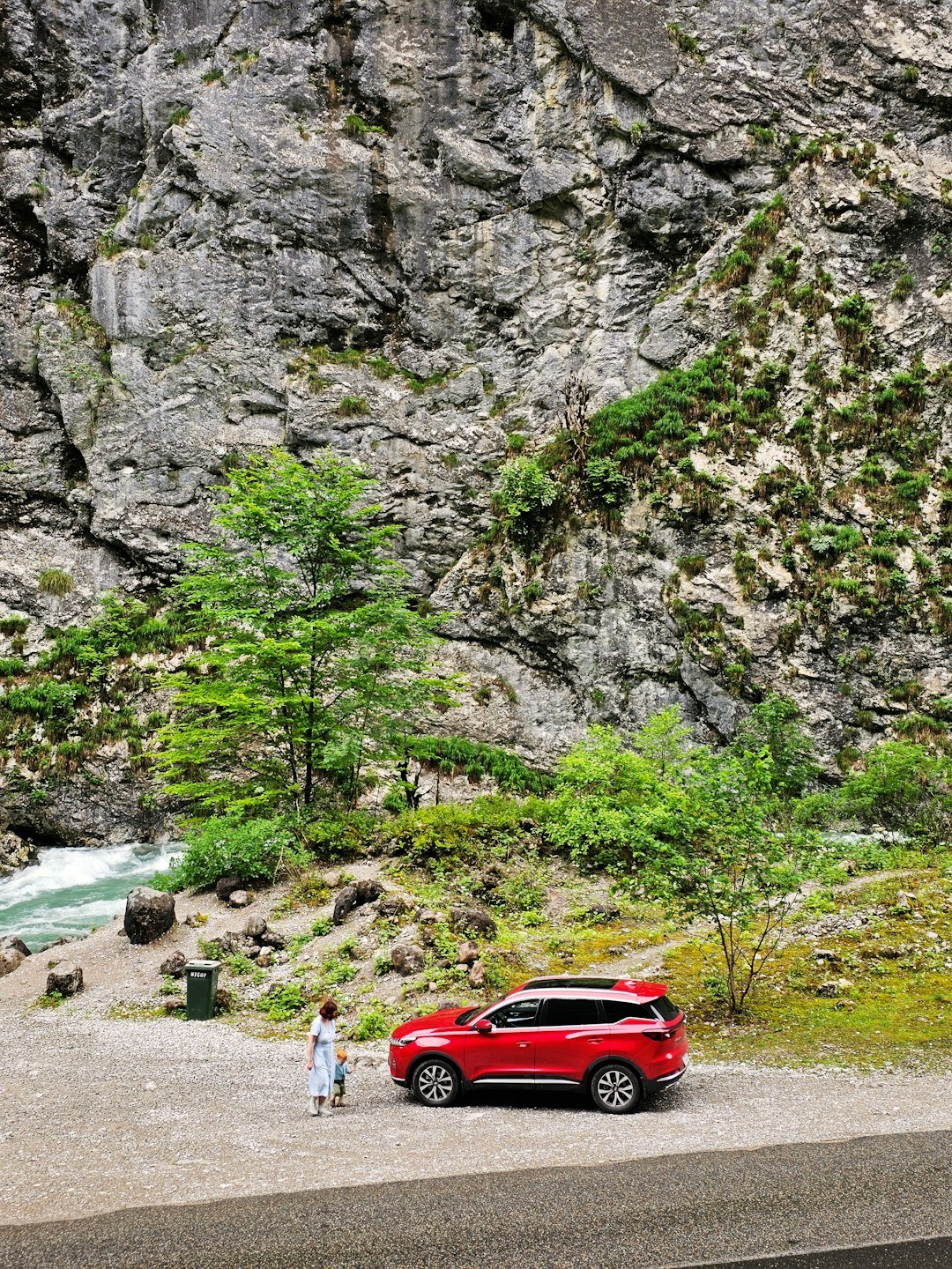 A red car parked on the side of a mountain road