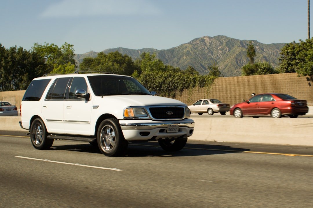 White suv driving on a highway with mountains.