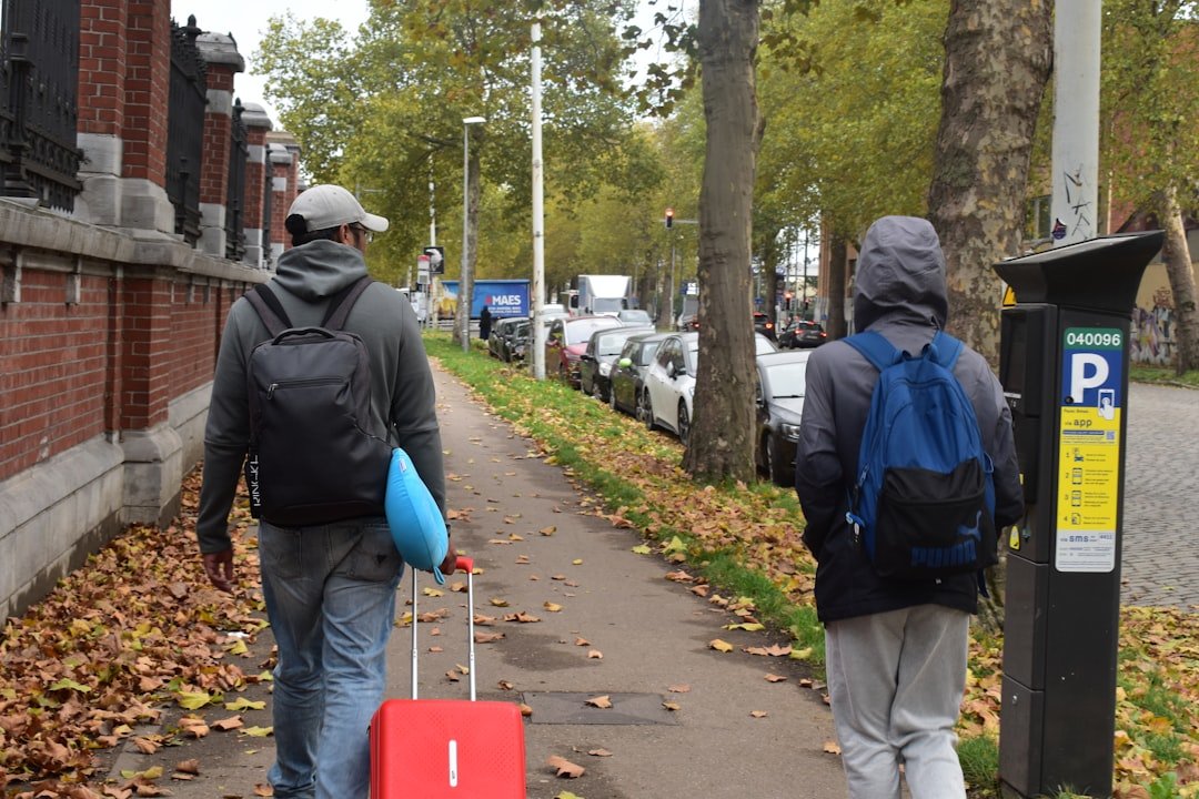 Two people walking down a sidewalk with luggage