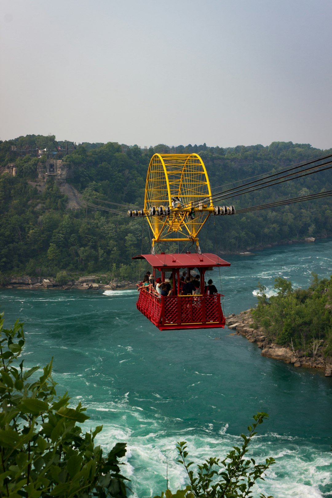 Yellow aerial tramway car over rushing river rapids