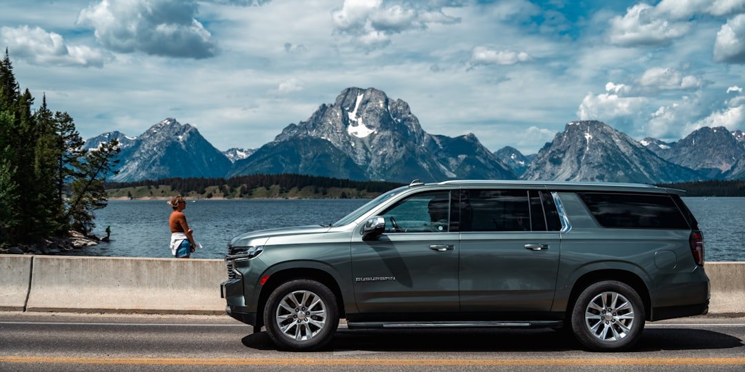 Suv parked by a lake with mountains in background