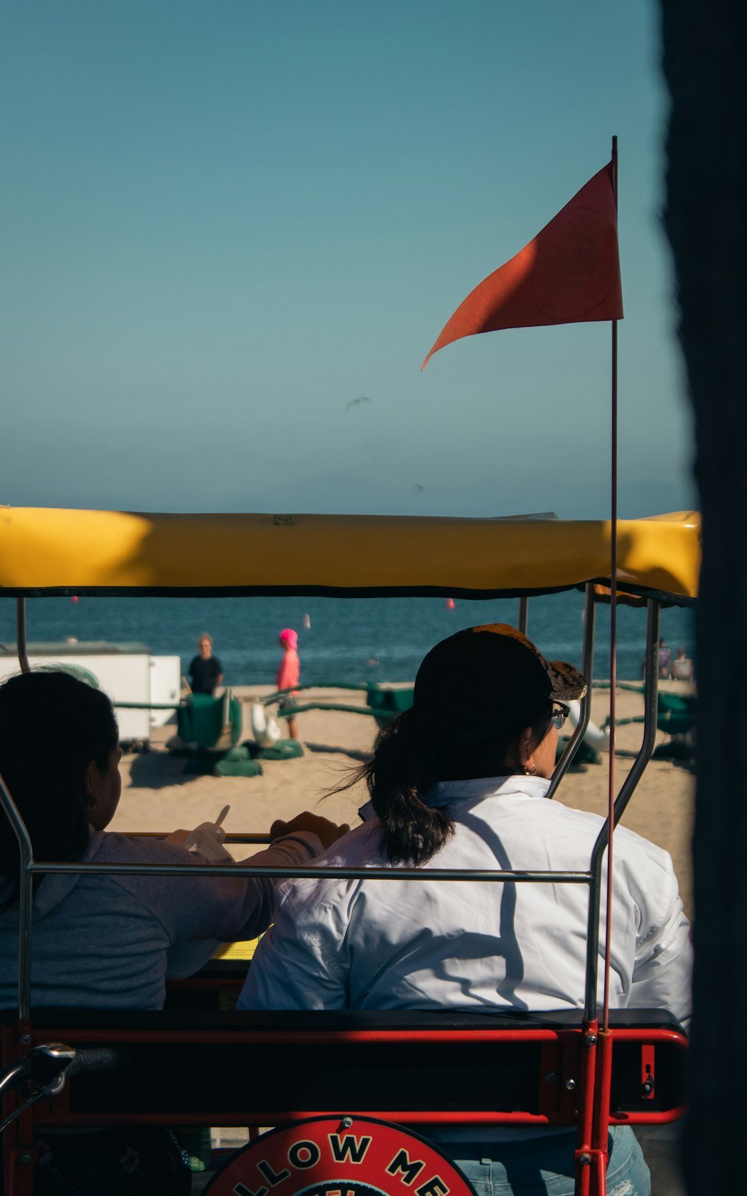A man and a woman riding in a cart on the beach