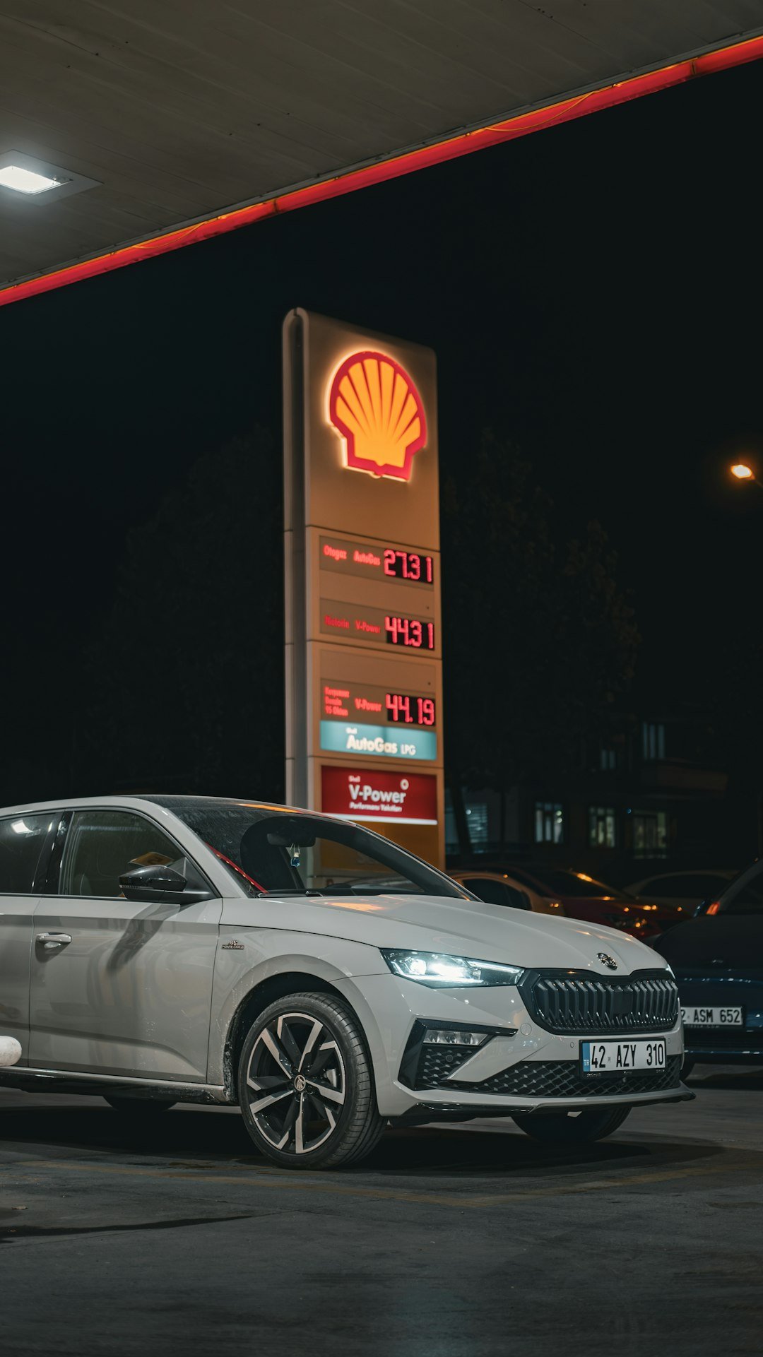 A silver car parked in front of a shell gas station