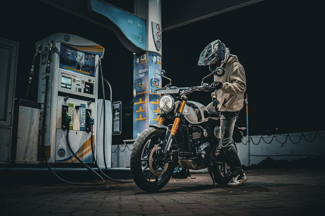 Rider with motorcycle at a gas station at night.