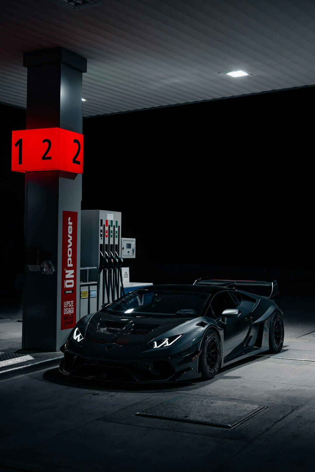 a black sports car parked at a gas station