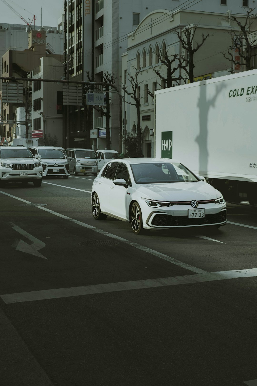 a white car driving down a street next to tall buildings