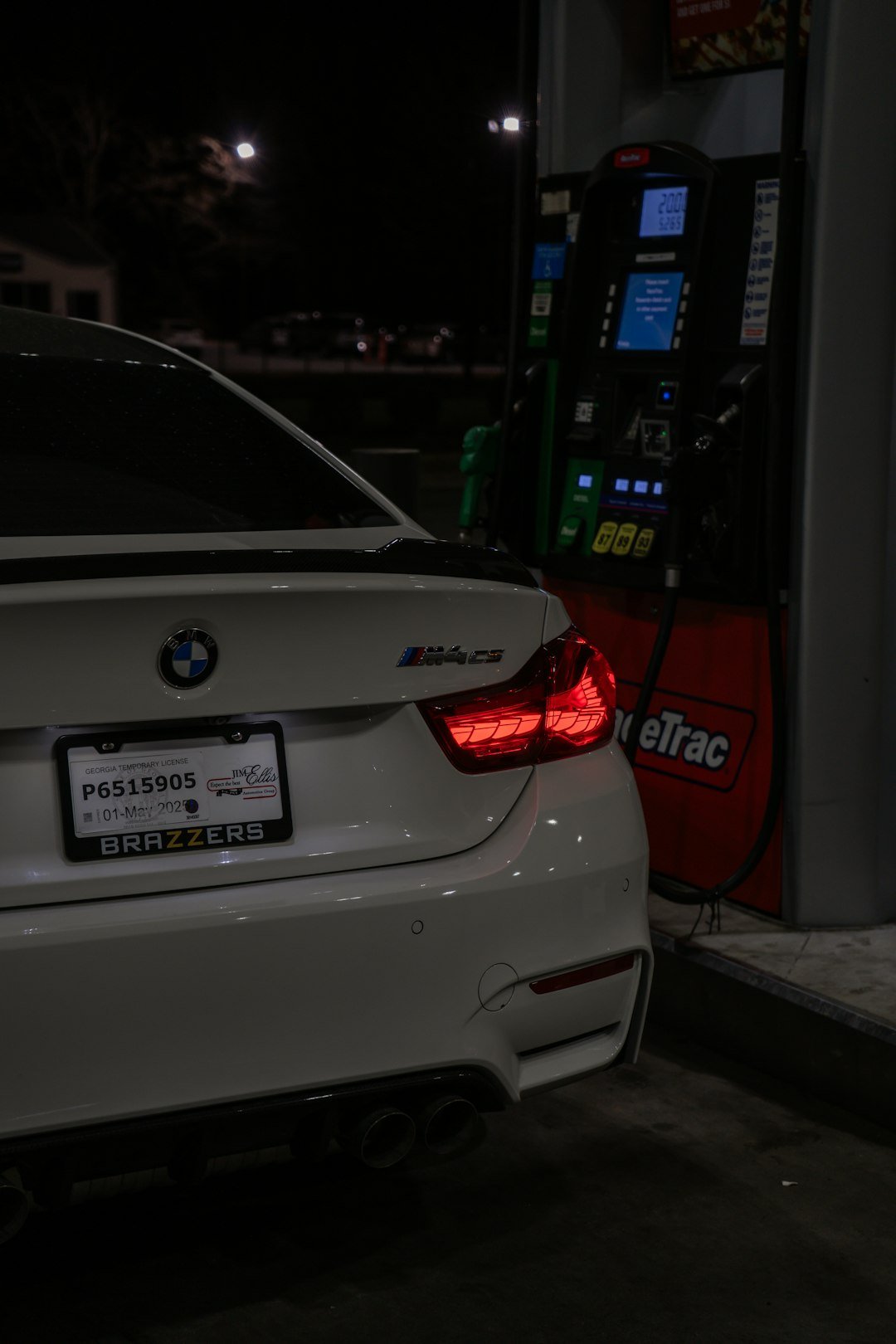 A white BMW m4 is refueling at night.