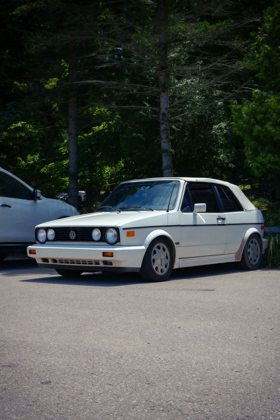 A white car parked next to a white car in a parking lot