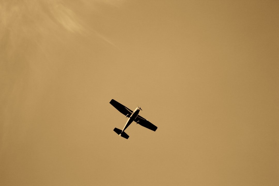 A small airplane flying in a sepia-toned sky.