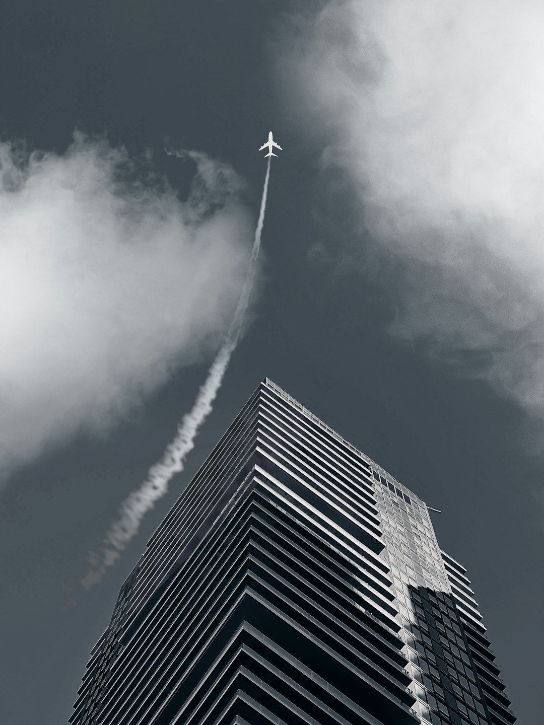 a plane flying in the sky over a tall building