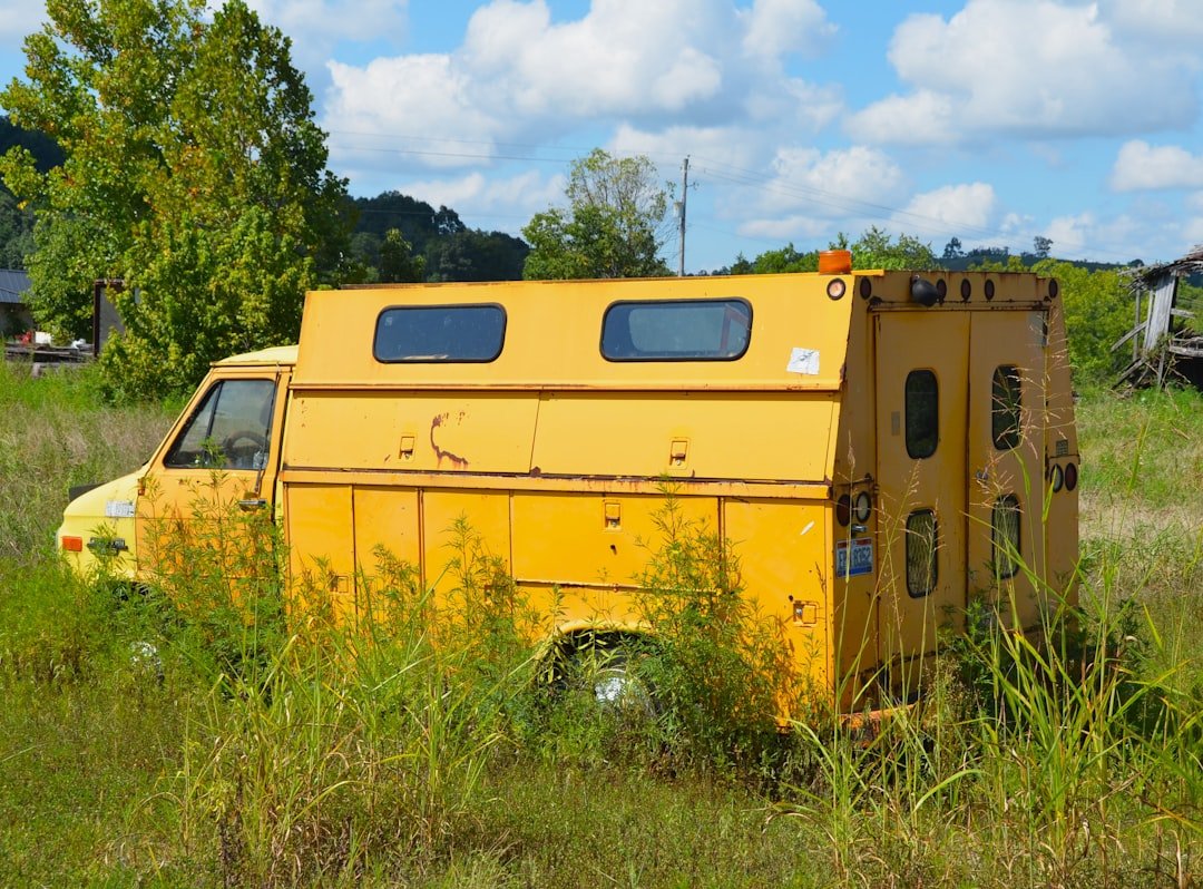 Yellow utility truck abandoned in overgrown field