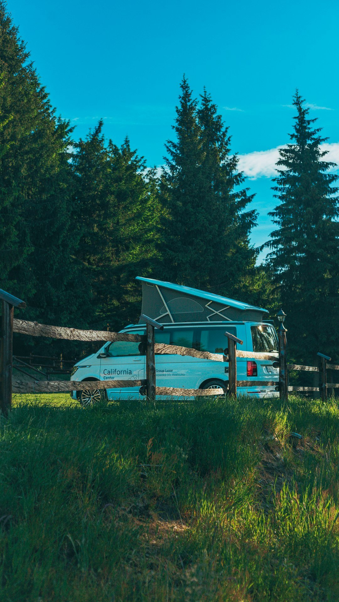 A van parked in a field next to a fence