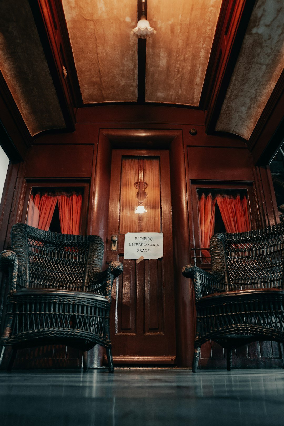 two wicker chairs sitting in front of a wooden door