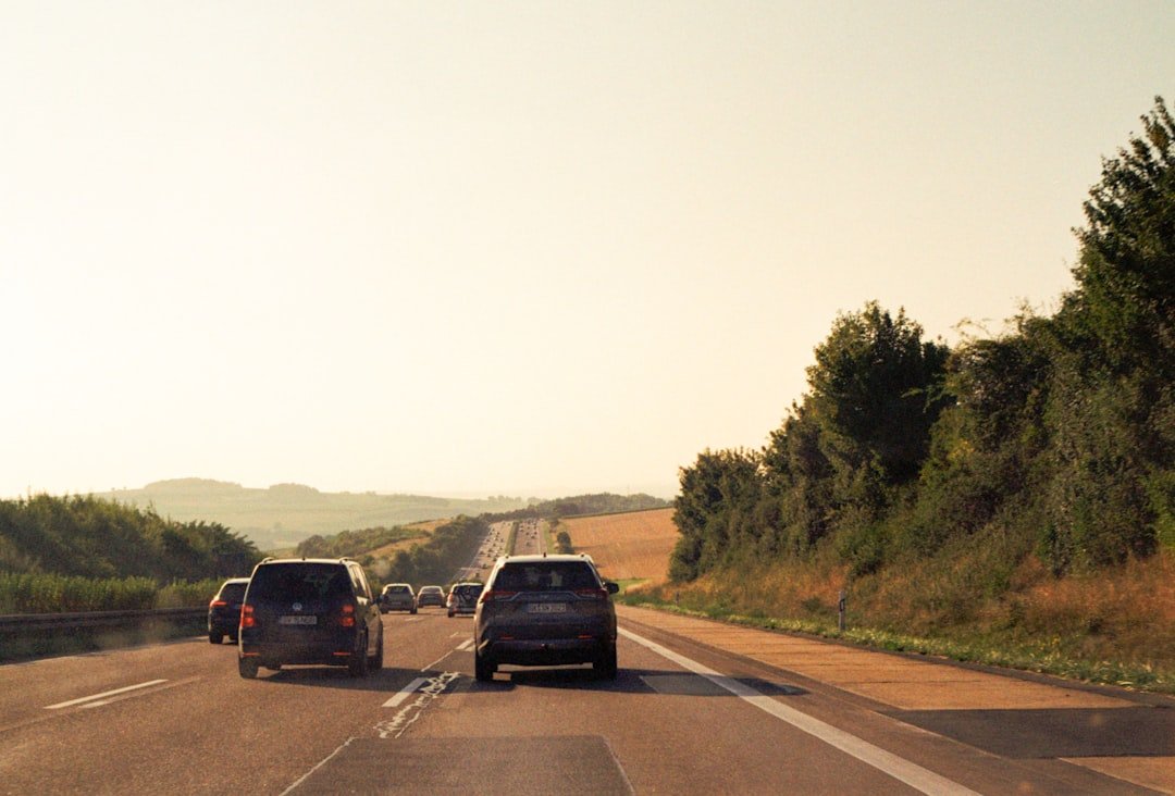 Cars driving on a highway towards rolling hills.
