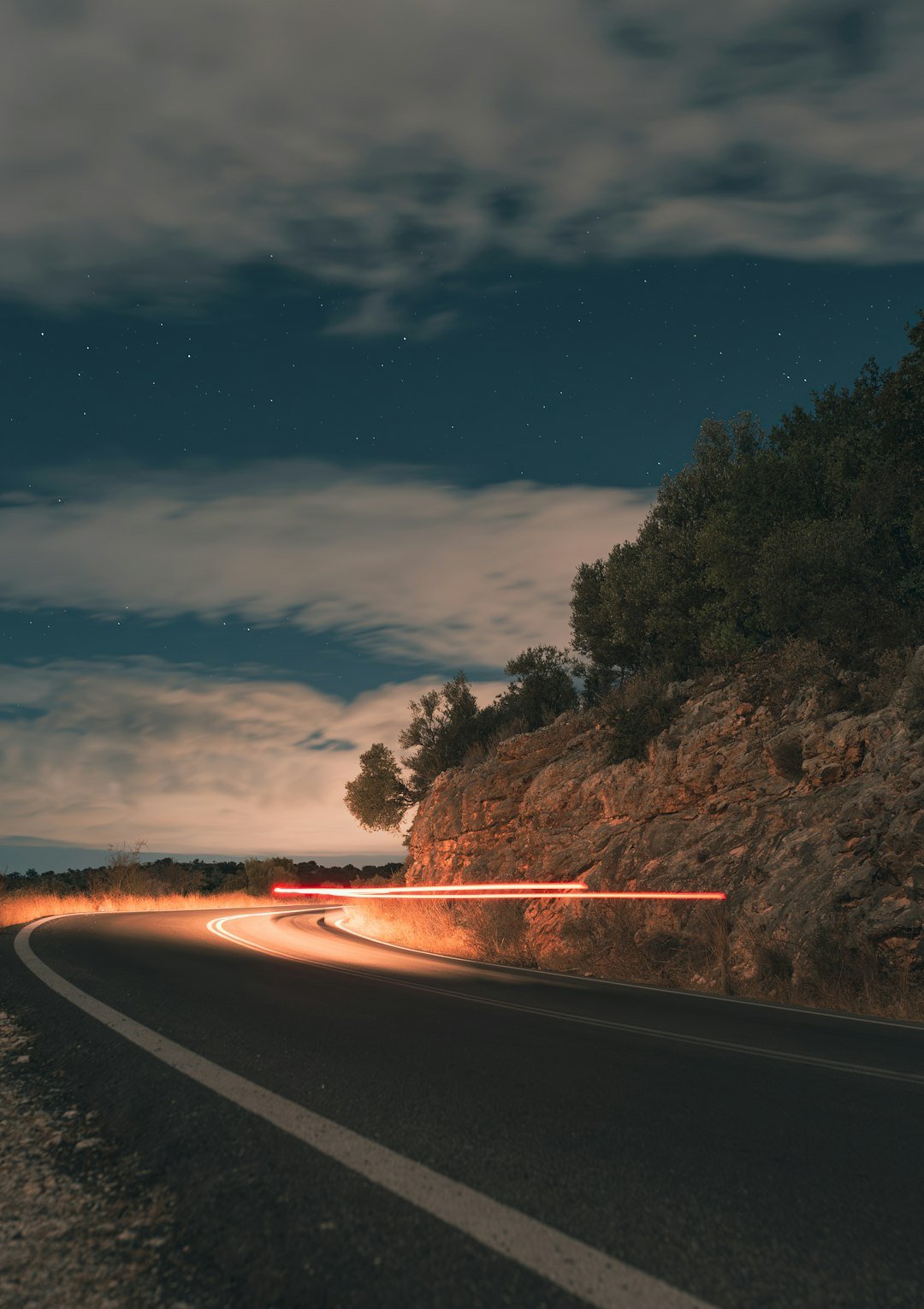 Car light trails on a winding road at night