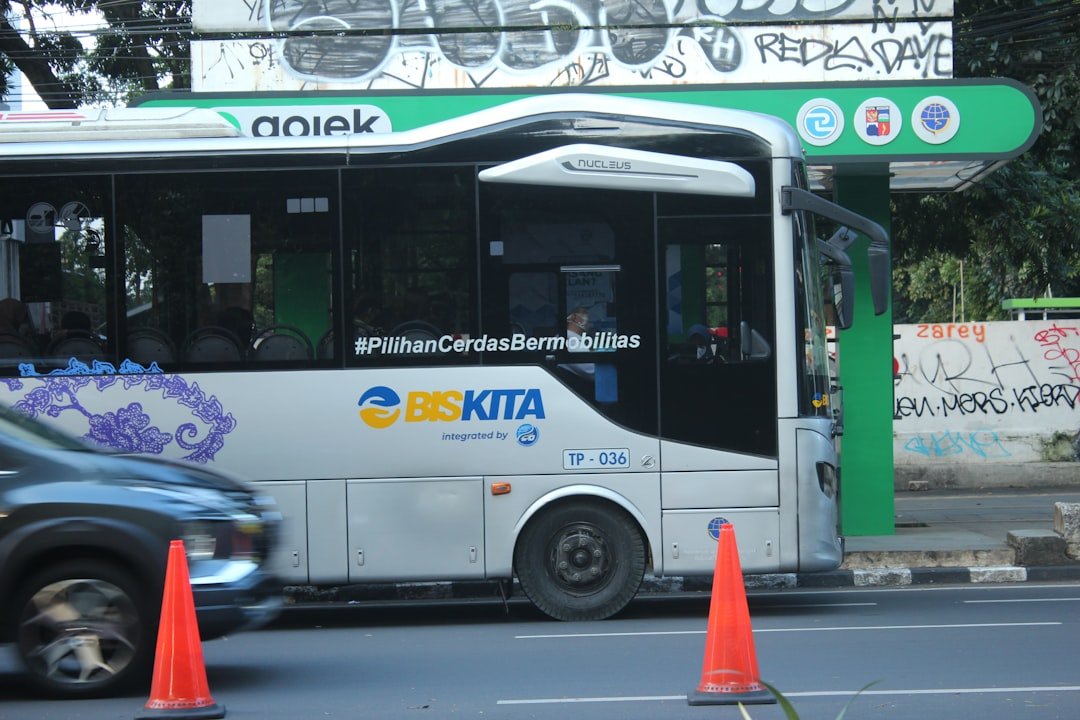 a white bus driving down a street next to traffic cones