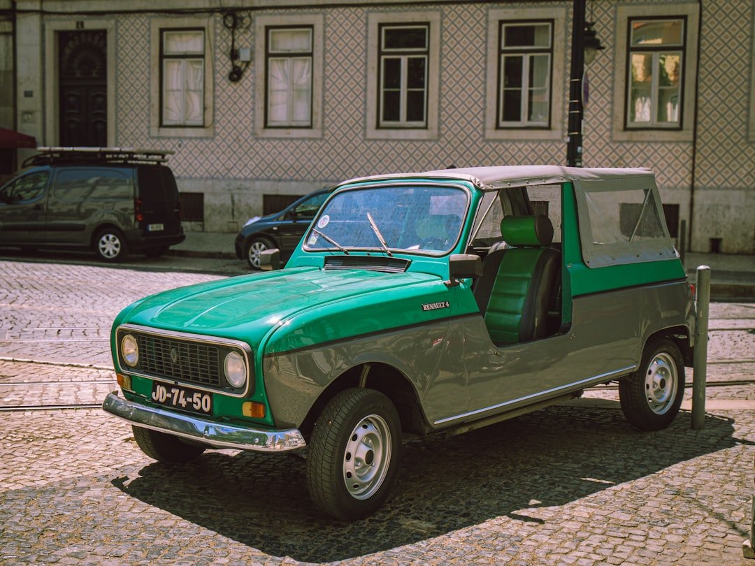 A green and gray vintage car parked on a street.