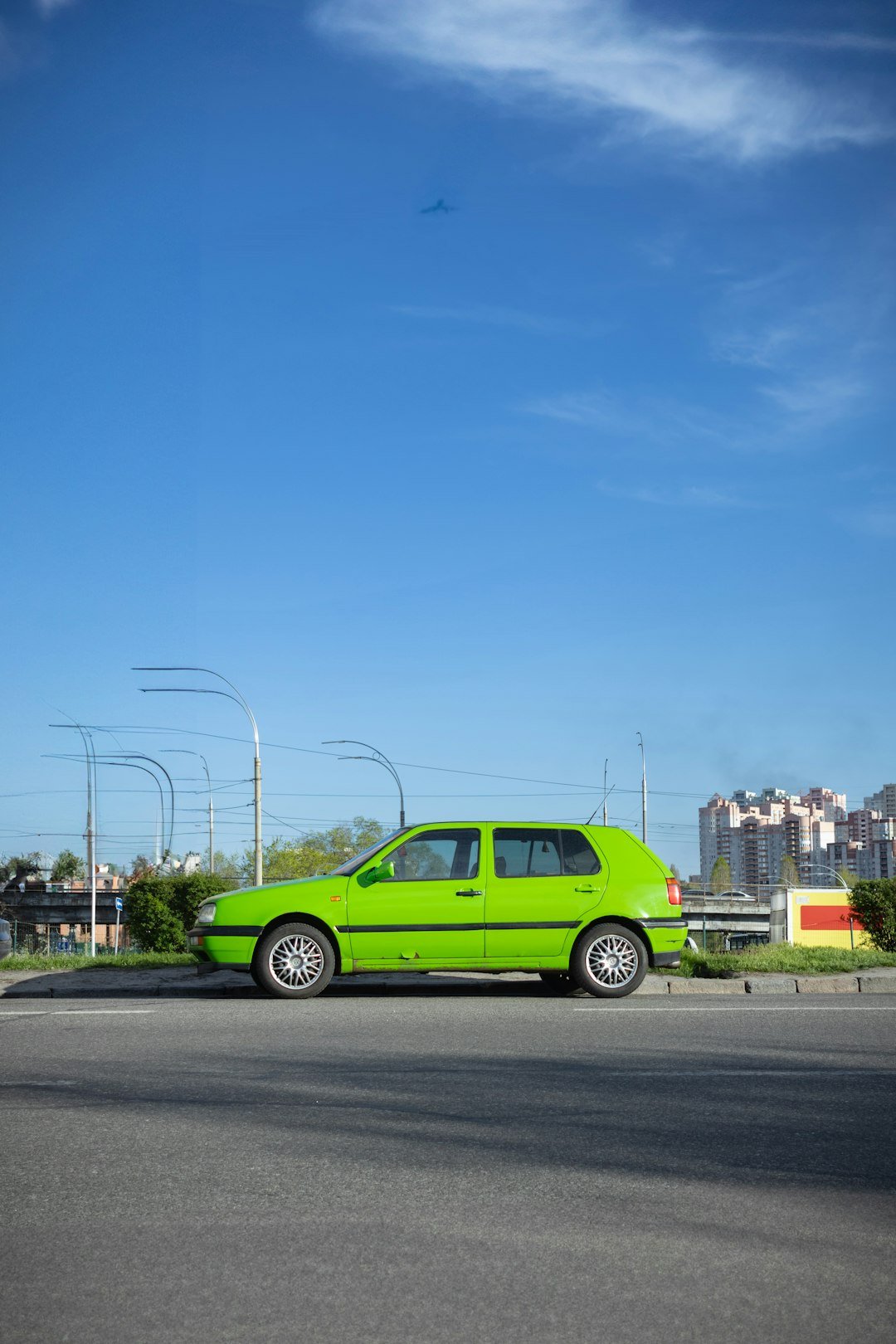 A bright green car is parked next to the road.