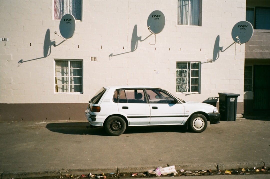 white suv parked beside white concrete building during daytime