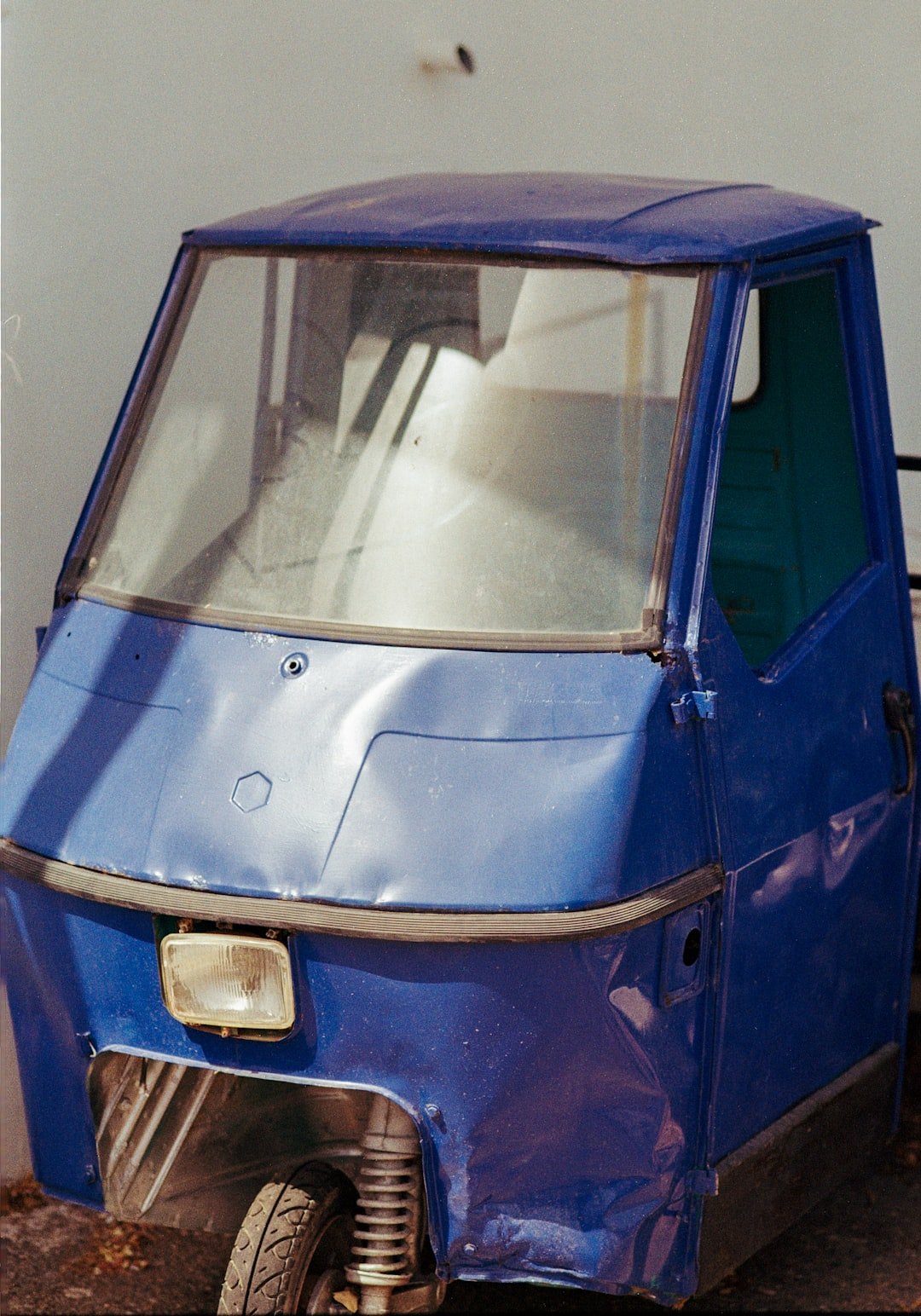 A blue car parked next to a white wall