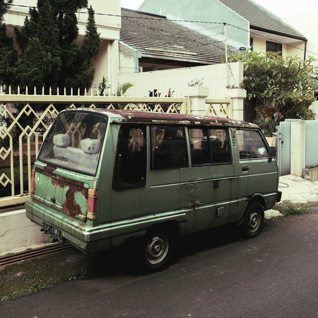 green and white volkswagen t-2 parked beside white concrete building during daytime