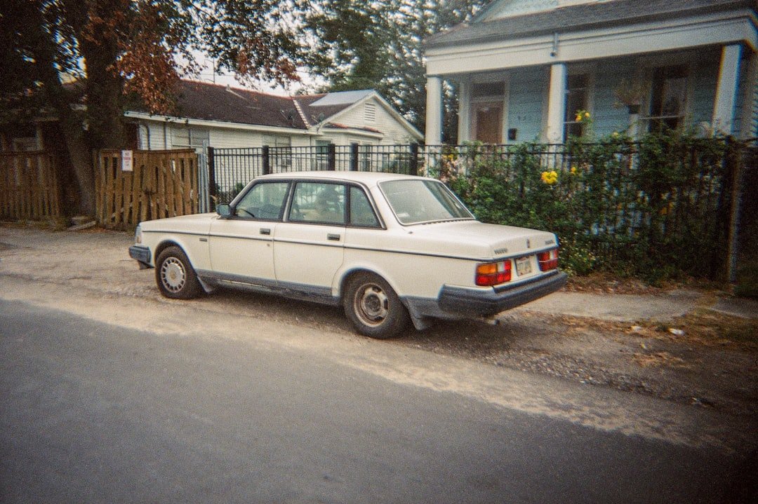 A white car is parked on a dirt road.
