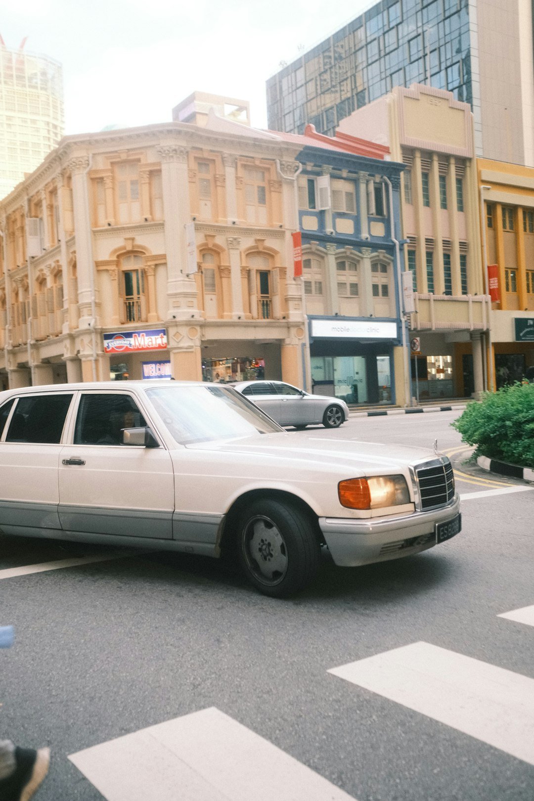 A white car driving down a street next to tall buildings